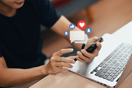 Cropped image of man hand typing on smart phone with notification icons of like, message and comment.の写真素材