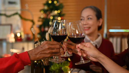 Family toasting wine at Christmas dinner, focus on hands and wine glasses. Holidays and celebration...