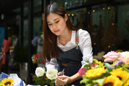 Small business owner florist wearing apron making bouquet, decorations and arrangements flower studio.の写真素材