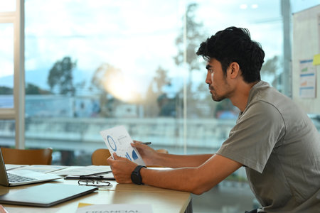 Side view of young start up businessman in casual clothes working in bright modern office.の写真素材
