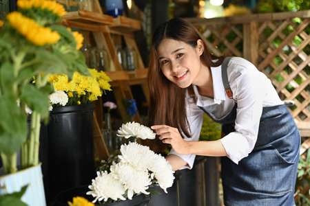 Successful small business entrepreneur in apron standing with flowers at rustic flower shop.の写真素材