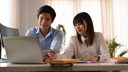 Two smiling young developer team collaborating and developing template layout for mobile application in creative workplace.の写真素材