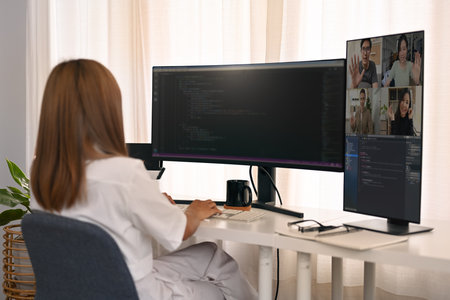 Rear view of female developer having video conference and working with coded data on computer screen.の写真素材