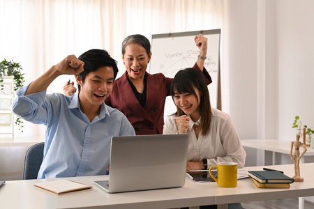 Happy young employee with senior manager celebrating corporate success or victory at office.
