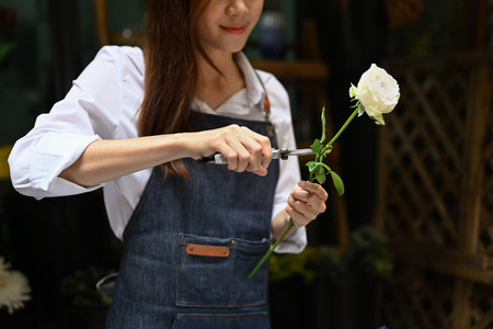 Cropped shot of female florist cutting branches , creating beautiful bouquet her floral shop.