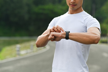Sportsman resting after jogging and checking his heart rate data on smartwatch. Healthy lifestyle, workout and wellness concept.の写真素材