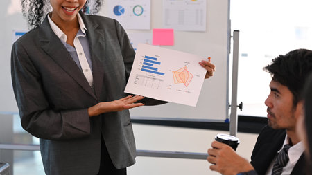 Smiling woman project manager holding financial document, giving presenting new marketing strategy in corporate briefing.の写真素材