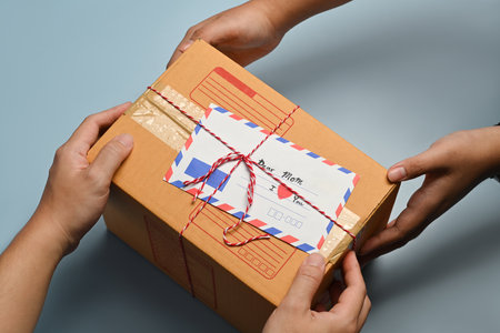 Above view of hands holding gift box with greeting card, preparing present for family during holiday...