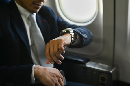 Cropped shot of businessman in black suit checking arrival time on his watch during business travel...