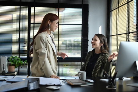 Two female colleagues enjoying conversation, discuss work or personal during break in office.の写真素材