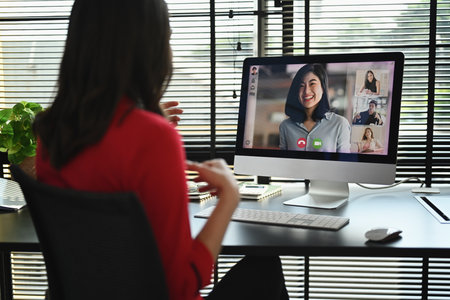 Back view of female entrepreneur having video call, discussing issues remotely online with diverse coworkers on computer.の写真素材
