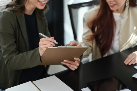 Cropped shot of caucasian female employee pointing on tablet, sharing ideas or discussing team project with her colleague.の写真素材