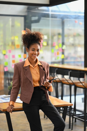 Portrait of successful start up businesswoman in stylish suit sitting in modern office and smiling to camera.の写真素材