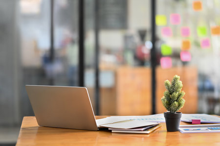 Modern creative office interior with laptop computer, documents and various office supplies on wooden table.の写真素材
