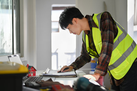 Engineer or building inspector in yellow vest checking and inspecting progressing work in...