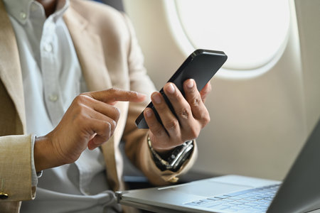 Businessman passenger working on laptop and typing text on mobile phone using wireless connection on...