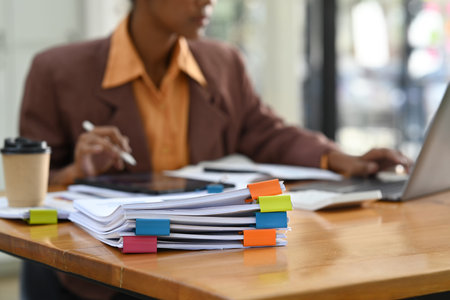 Selected focus on documents. Stack of report paper documents on office desk with business woman...