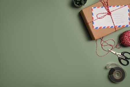 Gift boxes, clews of rope, adhesive tape and scissors on green background with copy advertising space. Preparation for holidays.の写真素材