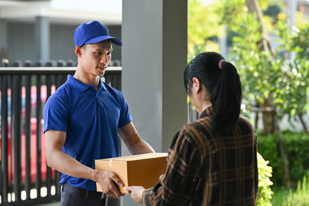 Delivery man giving postal package to customer at doorway. Delivery service, post and shipping concept.の写真素材
