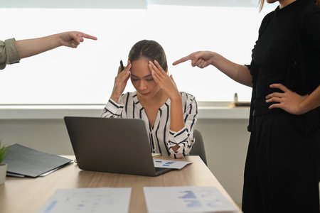 Frustrated young female employee receiving unfair reprimand rebuke, suffers from bad attitude at work. Stress at work concept.の写真素材