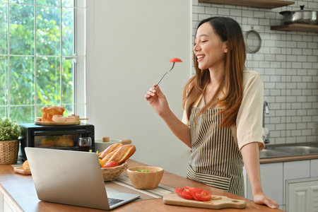 Pretty young woman eating fresh healthy vegan salad in kitchen. Diet, healthy lifestyle, vegetarianism lifestyle.の写真素材