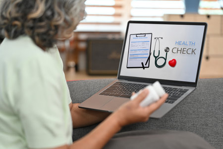 Mature female patient examining or checking her health online on laptop. Health insurance and health care services concept.の写真素材