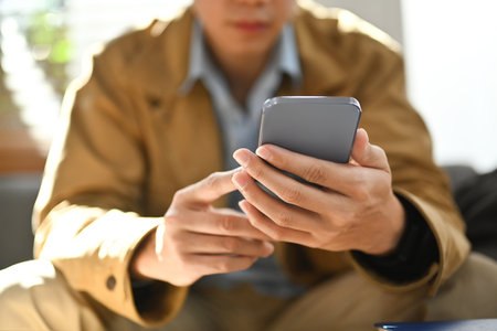 Selective focused on hands. Man chatting online in social network on smart phone while sitting on...