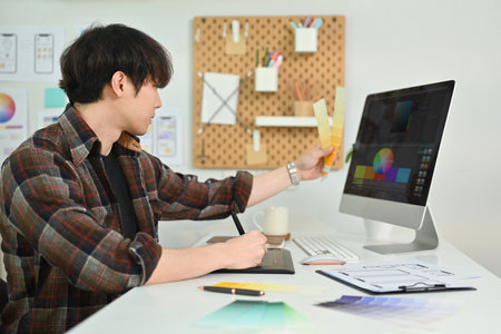 Side view of young man UX graphic designer working together for mobile application software design project at workstation.の写真素材