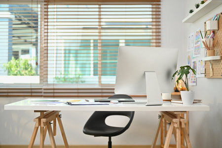 Modern workplace with computer monitor, wireframe, sketches of mobile application on screen, document and supplies on white table.の写真素材