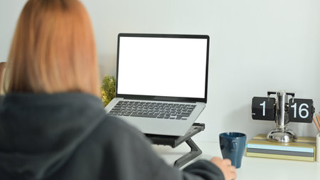 Back view of creative female freelancer sitting in comfortable workplace and working online with...