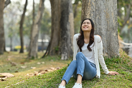 Happy millennial woman relaxing and fresh air in the park. Healthcare lifestyle and wellness concept.の写真素材