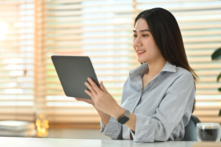 Attractive asian female marketing business manager expert using digital tablet at her working desk I bright office.の写真素材
