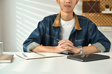 Image of young man in jeans jacket sitting at working desk in home office. Freelance, creative...