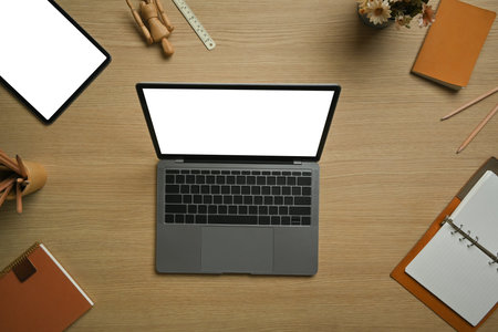 Above view of laptop computer, digital tablet surrounded by stationery on wooden working desk.の写真素材