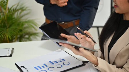 Cropped shot of business people using digital tablet, discussing project strategy at office meeting room.の写真素材