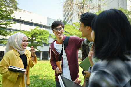 Multiethnic group of cheerful university student talking to each other after classes while walking in campus outdoors.の写真素材