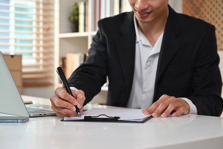 Cropped image of professional businessman in formalwear writing his strategy, signing a contract at working desk.の写真素材