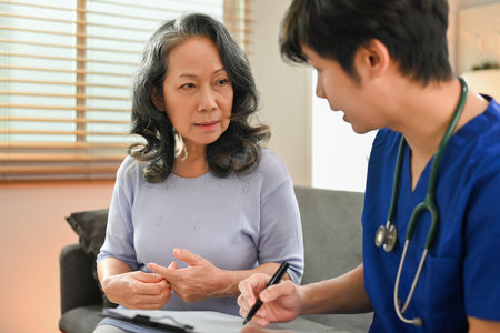 Medical worker giving a consultation, reporting medical results to middle age woman patient during home visit.の写真素材