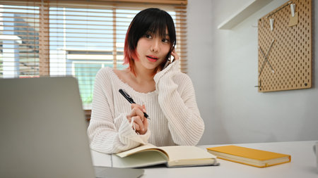 Young start up small business owner taking order from customer, talking on mobile phone at workplace.の写真素材