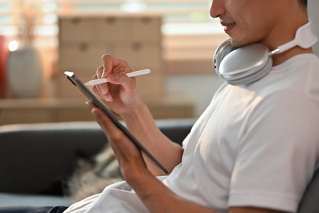 Side view of man in casual clothes using stylus pen writing on digital tablet screen. Communication,...