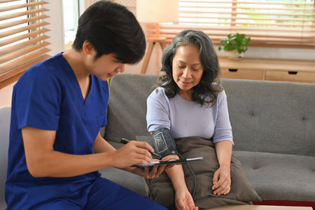 Asian male healthcare worker measuring blood pressure senior patient. Healthcare and home health...