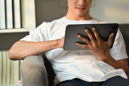 Cropped image of adult asian man working, browsing internet on digital tablet. People, technology and lifestyle.の写真素材