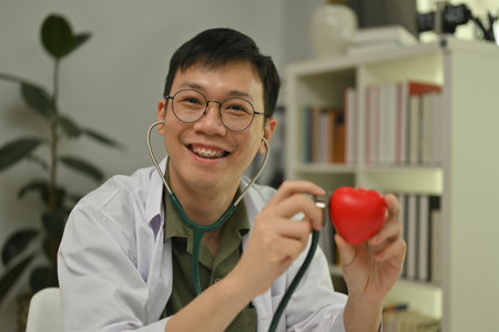 Young male doctor cardiologist holding a red heart. Cardiology, medicine, donation and healthcare concept.の写真素材
