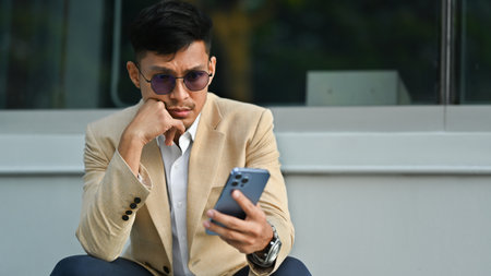 Young businessman in formalwear using smartphone in front of business center. Business, technology and lifestyle.の写真素材