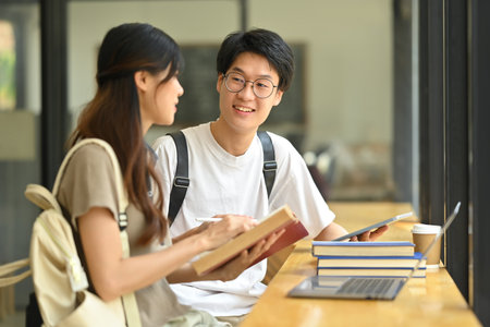Two happy students sitting in coffee shop learning and preparing for exams. Education and youth lifestyle concept.の写真素材