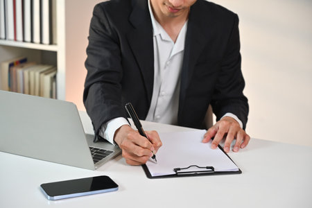 Businessman manager holding pen writing on documents, checking marketing report at desk.の写真素材