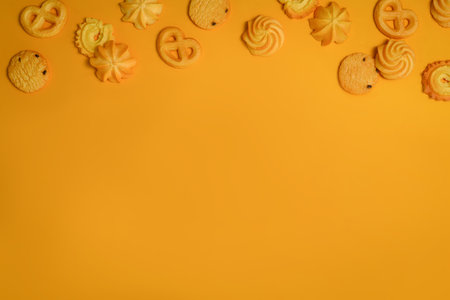 Fresh baked danish butter cookies on yellow background. Shot from up above, top view with copy space.の写真素材