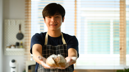 Portrait of male baker hands holding fresh sourdough bread. Healthy food, traditional bakery and pastry concept.の写真素材