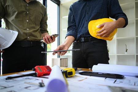 Cropped shot of two architect man using digital tablet, discussing work plan, industrial building...