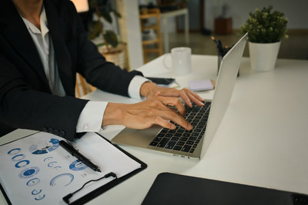 Businessman hands typing on laptop keyboard, checking financial data online or consulting client distantly.の写真素材